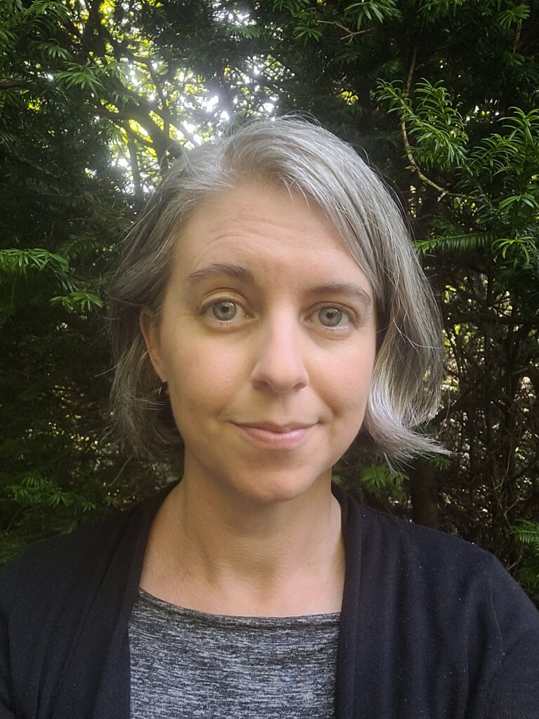 A medium-closeup photo of Erin Wiegand, a middle-aged white woman with chin-length grey hair and a slight smile.